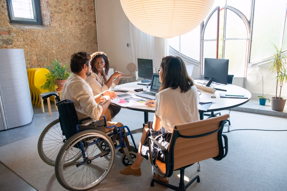 An inclusive team meeting in an office setting with individuals of diverse abilities collaborating.