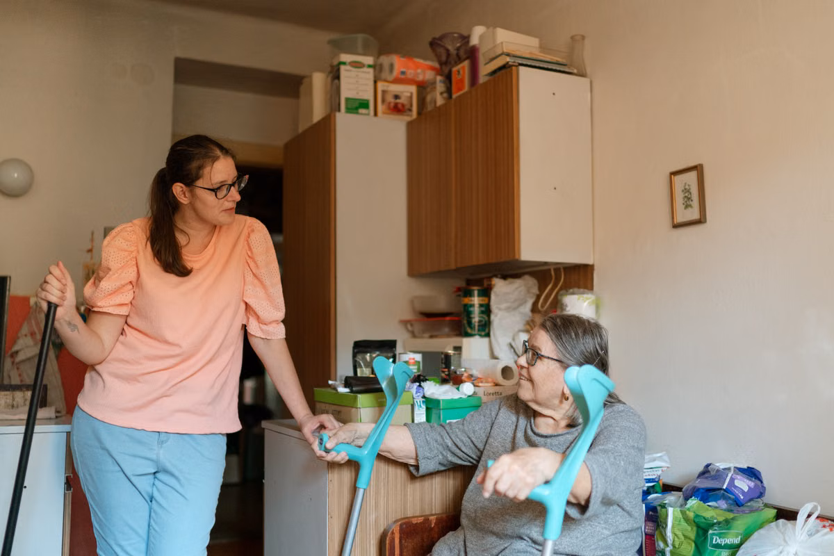 A compassionate caregiver assisting a person with a physical disability with everyday activities, showing support and care.